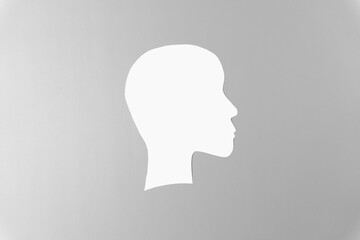 A simple white silhouette of a human head in profile against a neutral gray background.