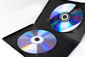 Two compact discs (CDs) are housed within an open black case, set against a bright white backdrop.
