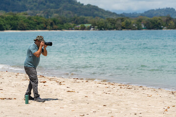 Man photographing on tropical beach with telephoto lens
