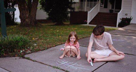 Brother and Sister Playing Tic Tac Toe with Chalk on Driveway – Fun Childhood Game on a Sunny Summer Day in Front Yard. Outdoor Summer Activity in Suburban Neighborhood