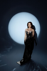 A woman in a metallic dress poses under a dramatic spotlight. Her confident stance and artistic...