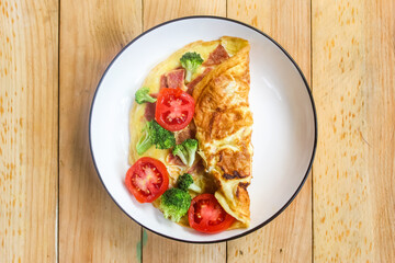 omelette with ham, broccoli and tomato mixture on a plate on a wooden table