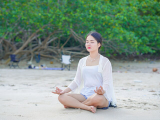 Asian woman yoga pose relaxation on sand beach sea embracing mindfulness. She enjoy active lifestyle health, exercise and self care. Generation Z people wellness, workout, leisure and mental healthy