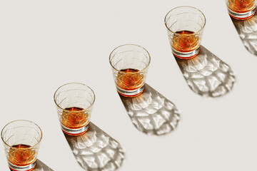 Crystal Whiskey Glasses at row with shadow and sunlight reflection on beige background, minimal neutral pattern, aesthetic top view summer still life, refraction at shine alcohol drink, caustic