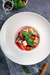 Salad with tomatoes, mozzarella and basil - Italian Caprese salad with olive oil and cherry tomatoes, Homemade served on a white plate, top view