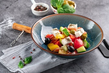 Vibrant Greek salad in a blue bowl, featuring tomatoes, cucumbers, olives, and feta cheese, sprinkled with herbs. Perfect for Mediterranean diet, ideal for healthy eating.