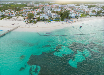 A beautiful beach with a clear blue ocean and white buildings in the background