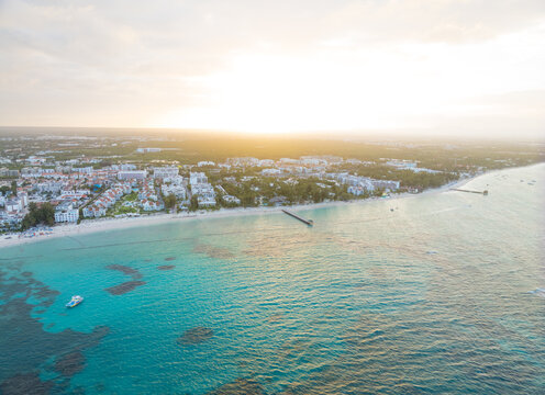 A beautiful blue ocean with a white sandy beach and a city in the background