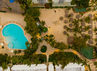A pool and a beach area with palm trees