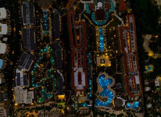 A nighttime aerial view of a resort with a pool and a hotel