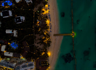 A nighttime aerial view of a beach with a pier and a row of houses