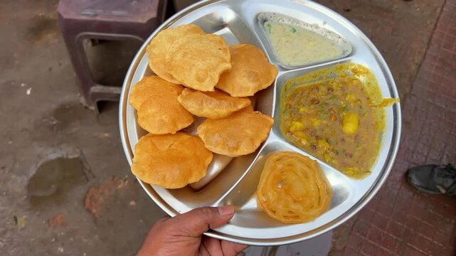Close up shot of puri bhaji served with potato curry along jalebi, raita at a Bihari shop in Dhanbad at daytime.