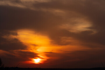 Warm orange sunset glow illuminating cloudy urban horizon silhouette.