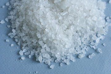 White sea salt on a blue background. Close up. Selective focus.
