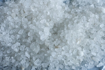 Close up of sea salt crystals on white background. Selective focus.