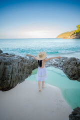 Woman tourist in white dress standing on the sand of the sea, relax moment of the woman at the edge of the sea beach in summer course
