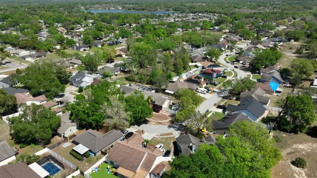 Brandon, Florida during sunny day. Quiet and charming suburb neighborhood with large houses between green trees in USA. Driving cars on street. Aerial orbit wide shot. Suburbia in America.