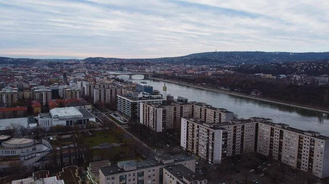 Drone establishing Budapest riverfront with a mix of historic and modern buildings along Danube River