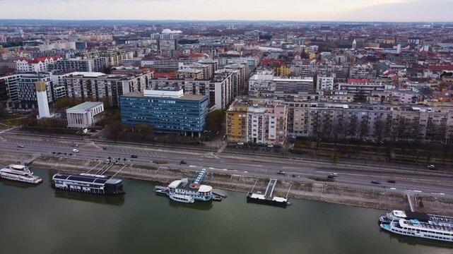 Drone establishing Budapest Reformed church on Pozsonyi Street, with vehicles crossing over Danube River at sunset