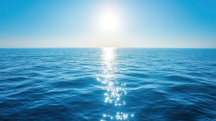 Obraz premium Sunlight glistens on the surface of a tranquil ocean, creating a shiny pathway across the water. The scene displays a cloudless blue sky and a peaceful atmosphere