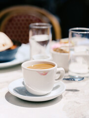 A coffee cup with a lipstick stain at an outdoor café table.