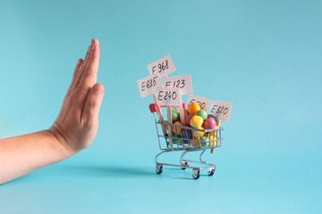 A cart with various colored food additives in close-up and a hand rejecting their use, a concept.
