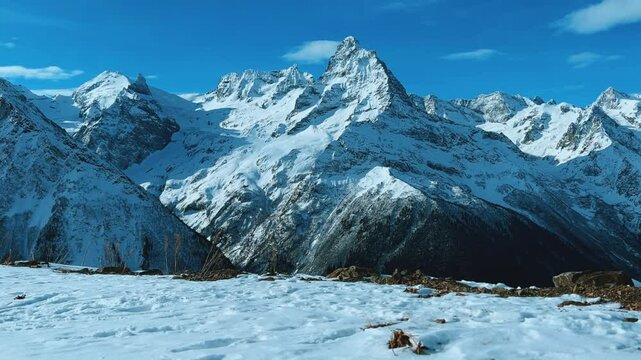 View of Dombay glaciers and mountain peaks in the winter sun. Panorama of the snow-capped Caucasus Mountains in sunny weather. Dombay-Ulgen and Moussa-Achitara mountains. Ski resort in Russia.