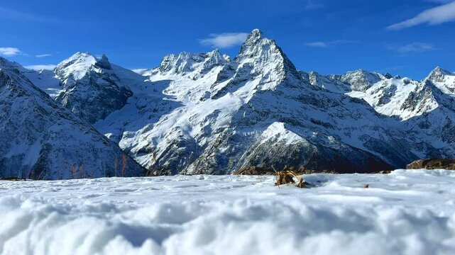 View of Dombay glaciers and mountain peaks in the winter sun. Panorama of the snow-capped Caucasus Mountains in sunny weather. Dombay-Ulgen and Moussa-Achitara mountains. Ski resort in Russia.