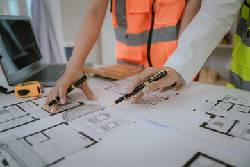 An architect or engineer is reviewing a digital blueprint on a tablet at a construction site. They are focused and confident in defining a strategy for the development of the project.