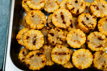 Roasted corn cobs of yellow succulent corn grilled on a wire rack