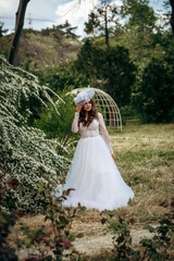 Fototapeta premium Elegant Bride in a Flowing White Gown Surrounded by Lush Greenery 