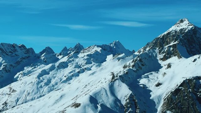 View of Dombay glaciers and mountain peaks in the winter sun. Panorama of the snow-capped Caucasus Mountains in sunny weather. Dombay-Ulgen and Moussa-Achitara mountains. Ski resort in Russia.