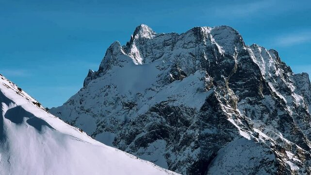 View of Dombay glaciers and mountain peaks in the winter sun. Panorama of the snow-capped Caucasus Mountains in sunny weather. Dombay-Ulgen and Moussa-Achitara mountains. Ski resort in Russia.