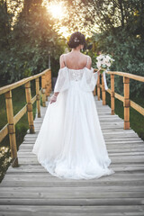 The bride in a white dress stands on the bridge
