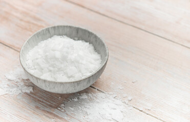 Magnesium chloride flakes in a bowl on rustic wooden table