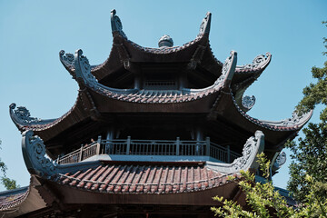 Fototapeta premium Stunning architectural details of a traditional Bai Dinh pagoda in Ninh Binh, Vietnam surrounded by lush green trees