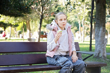 Child resting and eating apple fruit outdoors. Young girl 10 years old