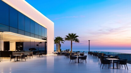 Fototapeta premium modern outdoor dining area with sleek furniture, palm trees, and stunning ocean view at sunset, creating serene atmosphere. 