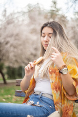 Woman in a park combing her hair with a hairbrush