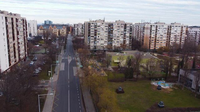 Overhead of a busy road in Budapest with multiple lanes of traffic surrounded by modern apartments, tracking left