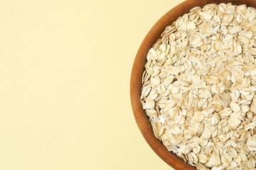 Composition with oatmeal flakes on beige background. Cooking breakfast