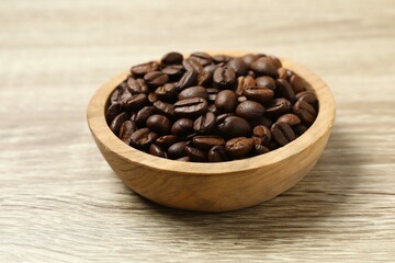 Coffee beans in a bowl on wooden background