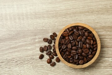 Coffee beans in a bowl on wooden background