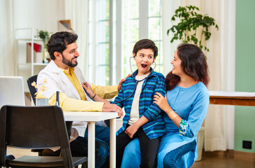 Playful Indian pediatrician makes little boy hear his heartbeat using stethoscope in hospital clinic