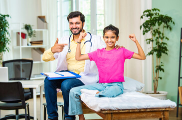 Indian Smiling young girl patient shows strength by flexing arm muscles with a friendly doctor