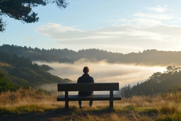 A person sits on a wooden bench, watching the morning mist fade. Gratitude lingers quietly in the stillness