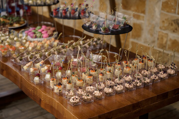 Catering service plate .appetizing sandwiches on plastic sticks range Sandwiches on a table the buffet. meat, fish, vegetable canapes on a festive wedding table outdoor