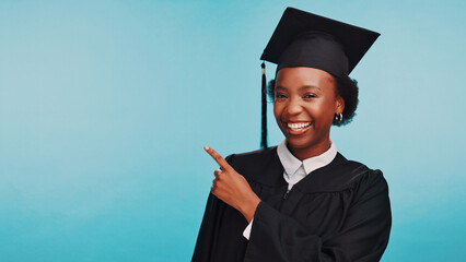 Black woman, graduation and point in studio portrait, education and mock up space by blue...