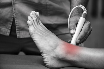 A physical therapist uses laser therapy on a patients ankle to reduce pain and promote healing. The...