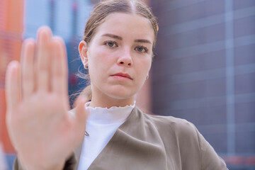 Serious young woman raising her hand in a stop gesture, expressing determination and...